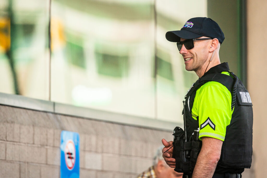 STA security officer in a bright yellow uniform and sunglasses standing outside a building, smiling.