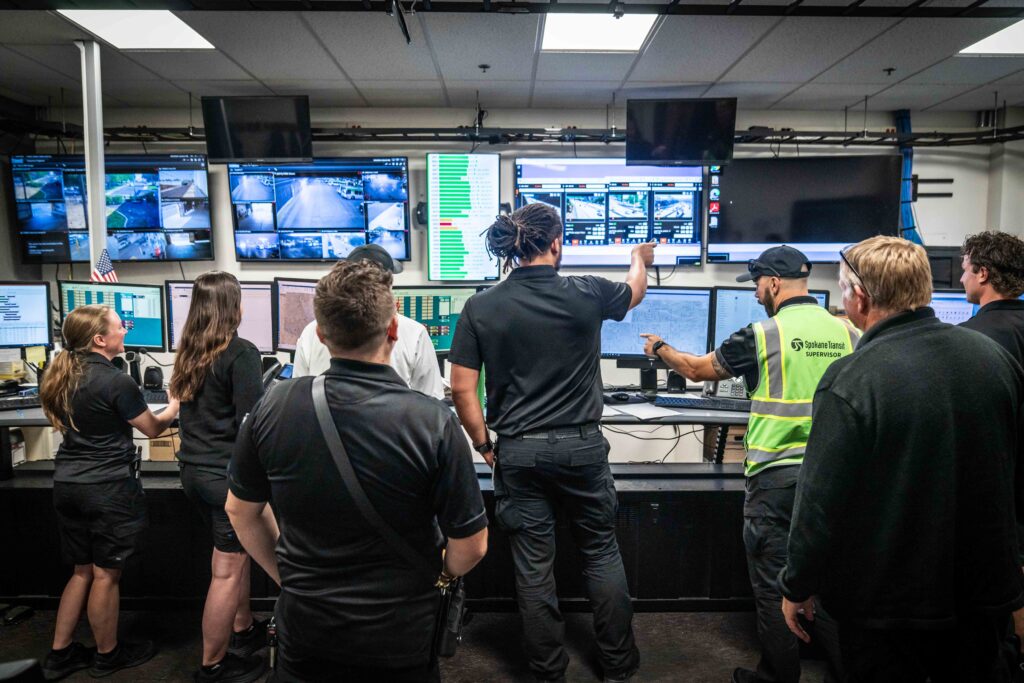 People in a control room analyzing multiple screens displaying surveillance footage.