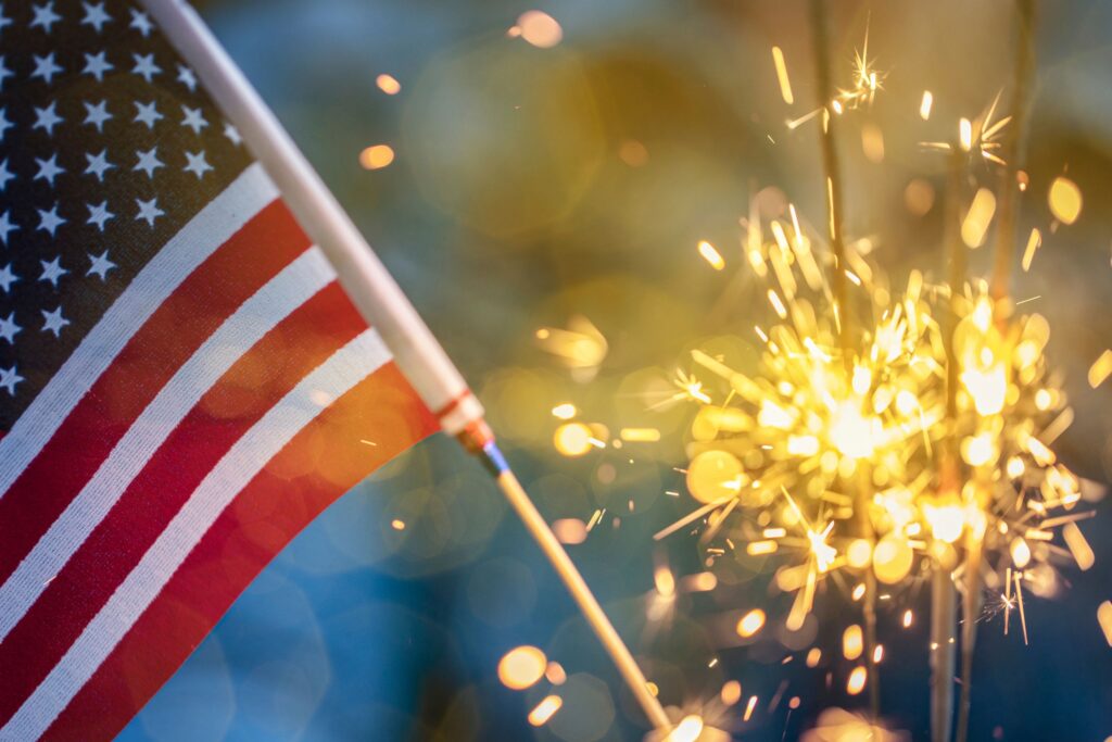 Close-up of the American flag with sparklers in the background, symbolizing celebration and patriotism.