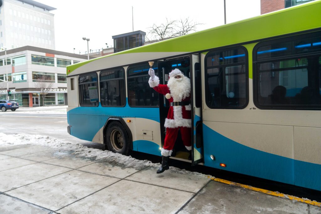 Santa Claus stepping off an STA bus, ringing a bell in downtown Spokane.