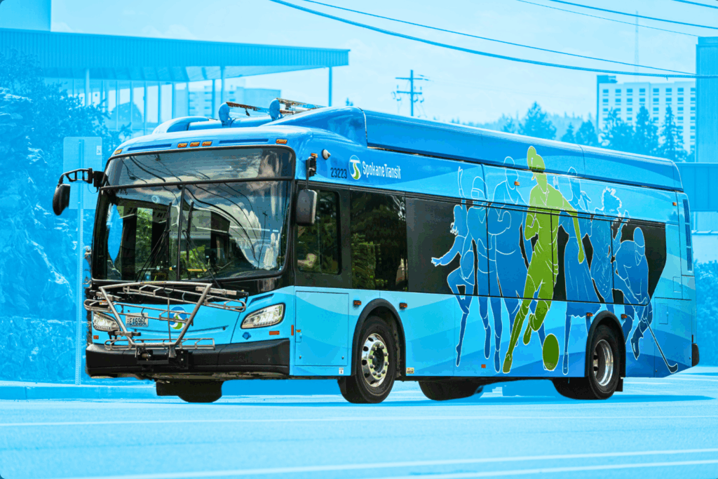 ALT: STA bus with sports-themed graphics driving on a sunny day.