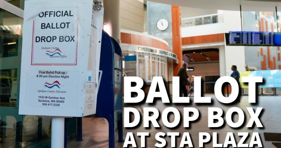 A ballot drop box at STA Plaza with signs indicating official ballot drop-off and an interior of a transit center in the background.